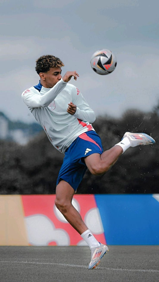 Person playing soccer on a field with a colorful wall in the background