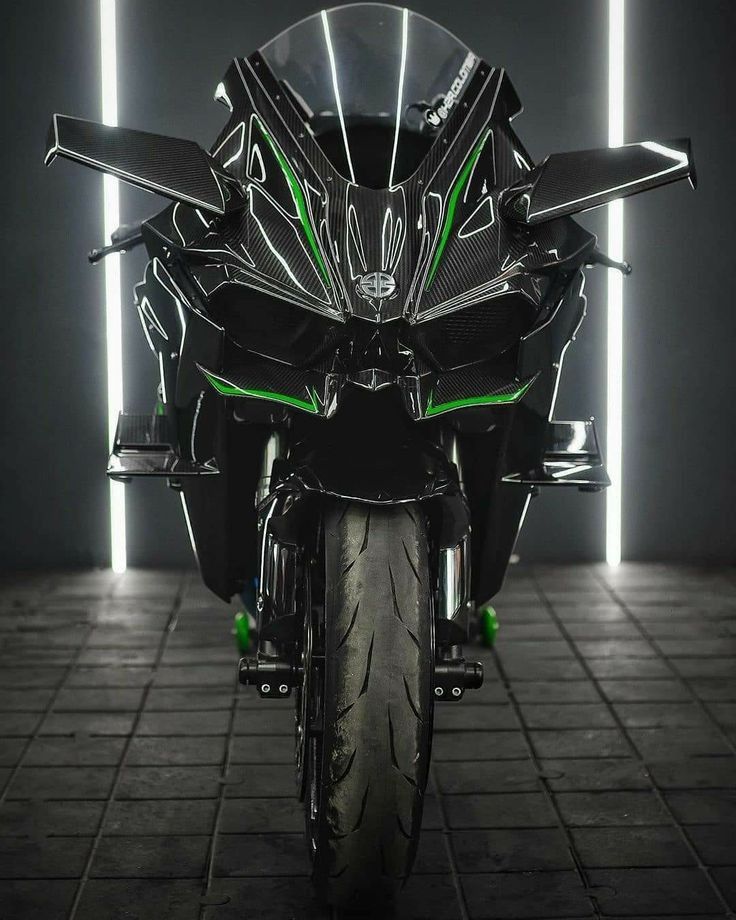 Black and green motorcycle in a dark room with reflective surface