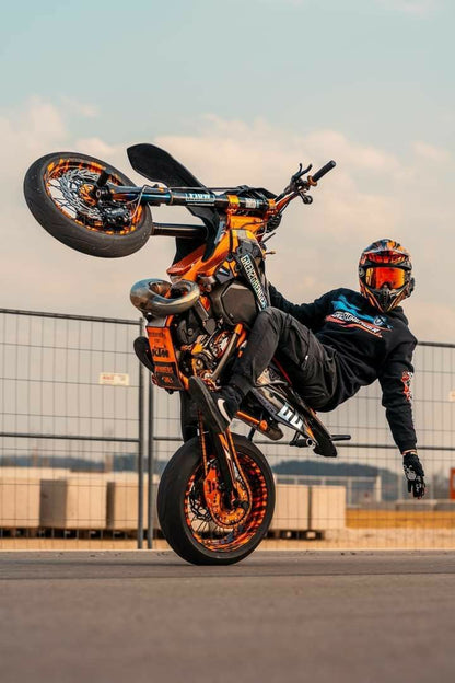 Motorcyclist performing a stunt with a bike in mid-air against a clear sky.