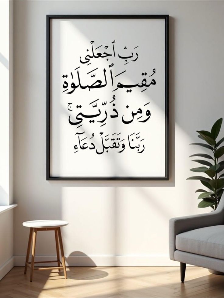Framed Arabic calligraphy on a wall in a room with a stool and plant.