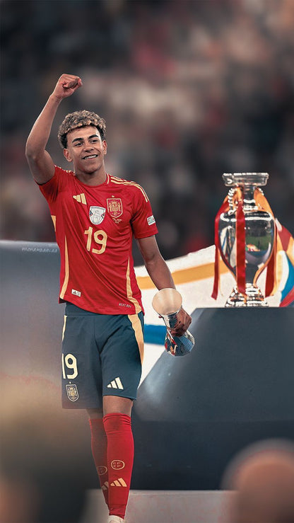 Soccer player in a red jersey with number 19, holding a trophy, with a blurred crowd in the background.