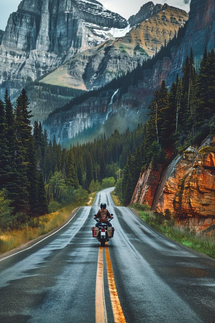 Motorcycle on a winding mountain road with towering cliffs and trees.
