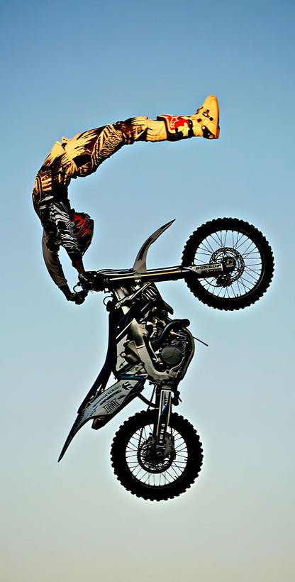 Person performing a backflip on a motorcycle against a clear blue sky