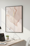 Abstract art print on a wall above a desk with a laptop and lamp.
