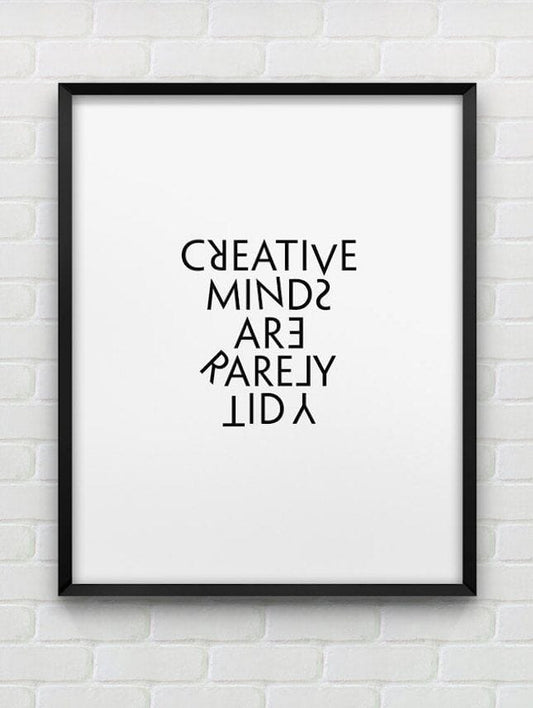 Framed poster with 'CREATIVE MINDS ARE RARELY LID' text on a white brick wall background