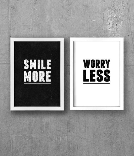 Two framed prints with motivational phrases 'Smile More' and 'Worry Less' on a concrete wall.